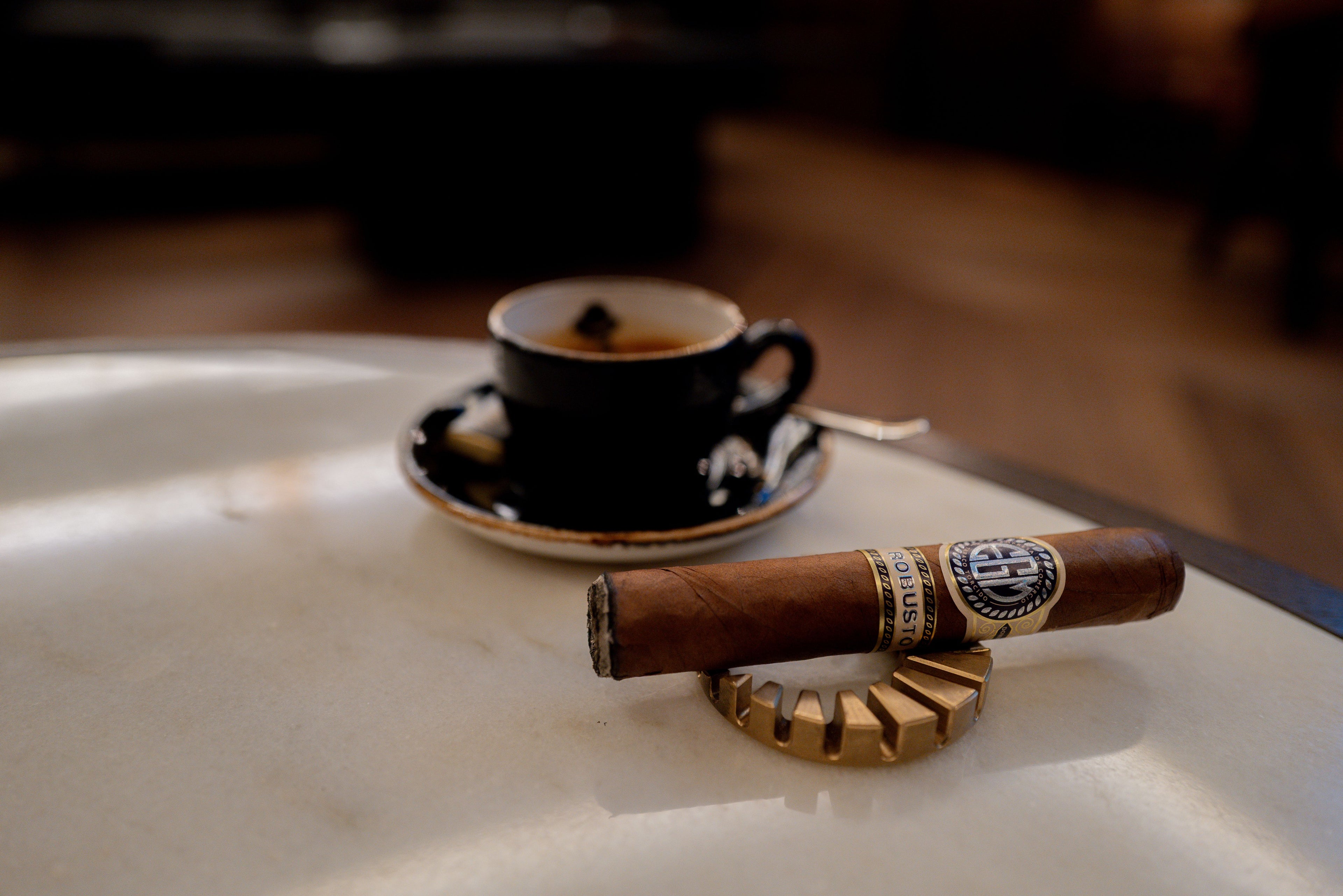 Cigar and coffee cup on a marble surface with a blurred background